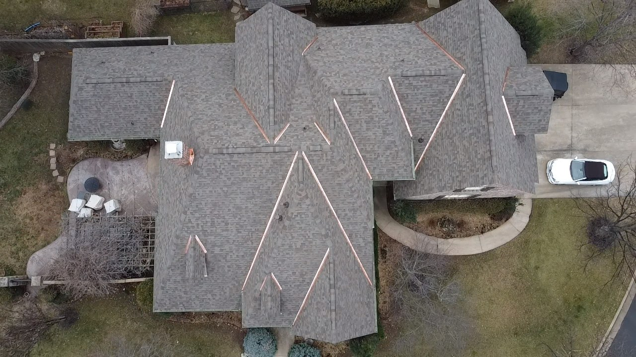 Aerial view of a Tulsa home with a gray shingle roof and copper roof accents, completed by Family Tree Roofing
