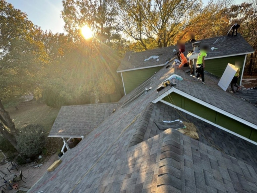 Family Tree Roofing crew installing new shingles on a two-story home in Broken Arrow at sunset