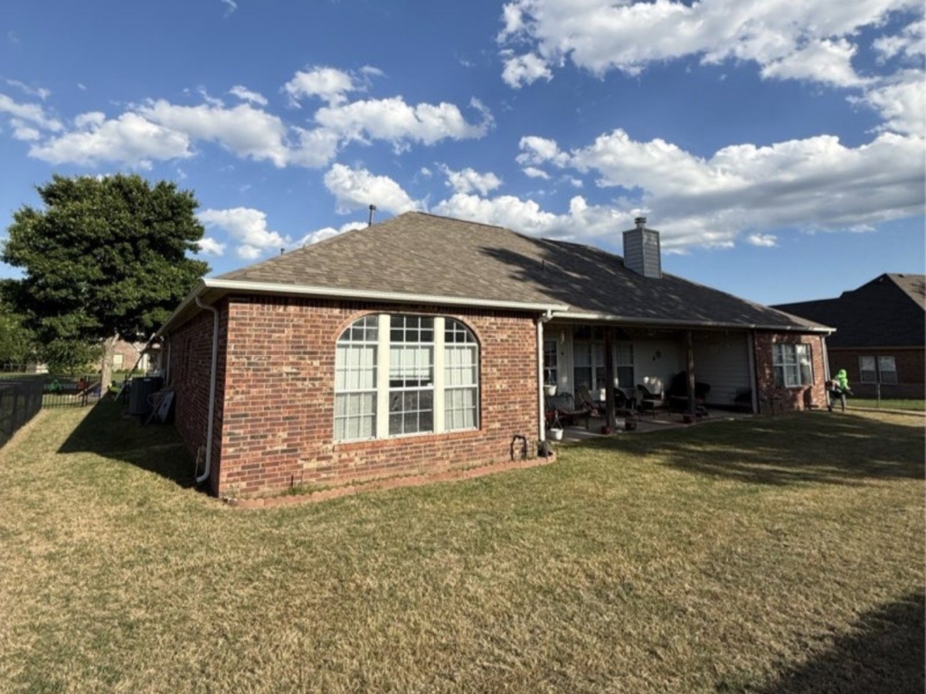 Finished shingle roof on a single-story brick home with a covered patio in Jenks