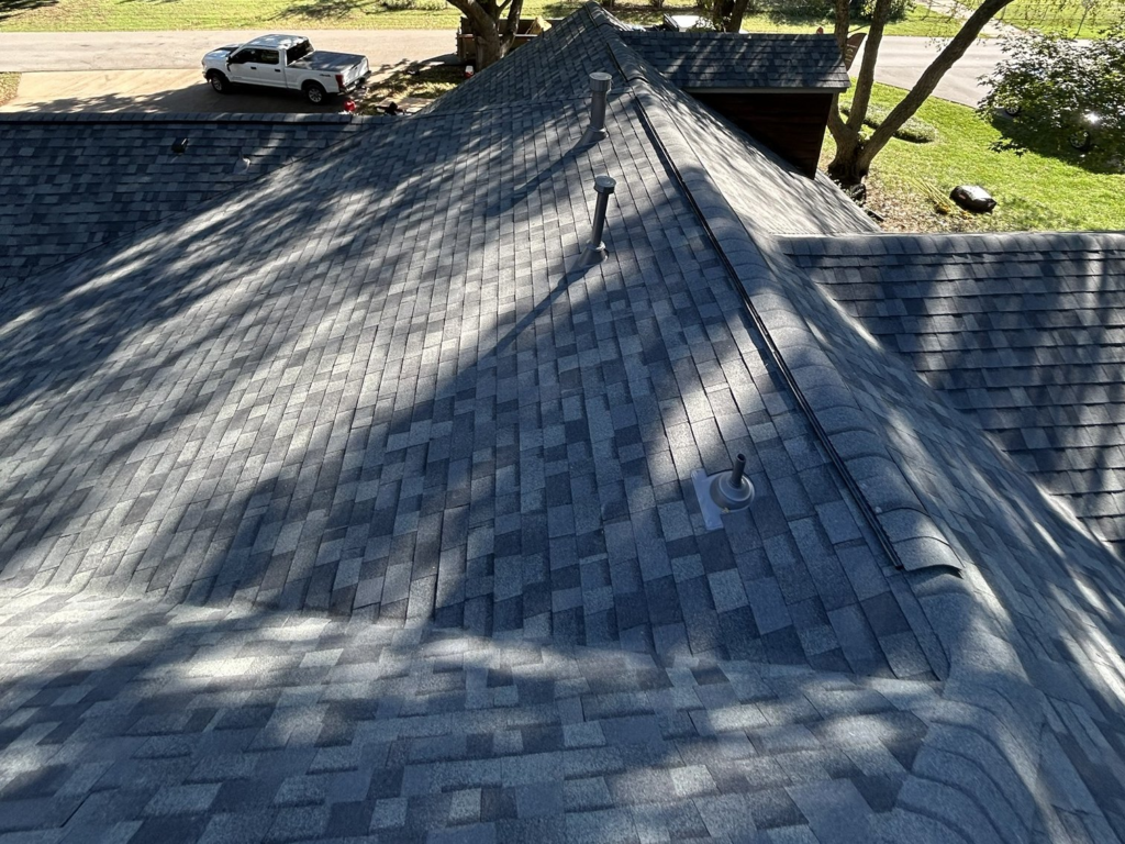 New shingle roof with a ridge vent running along the peak, plus new vent pipes and pipe boots