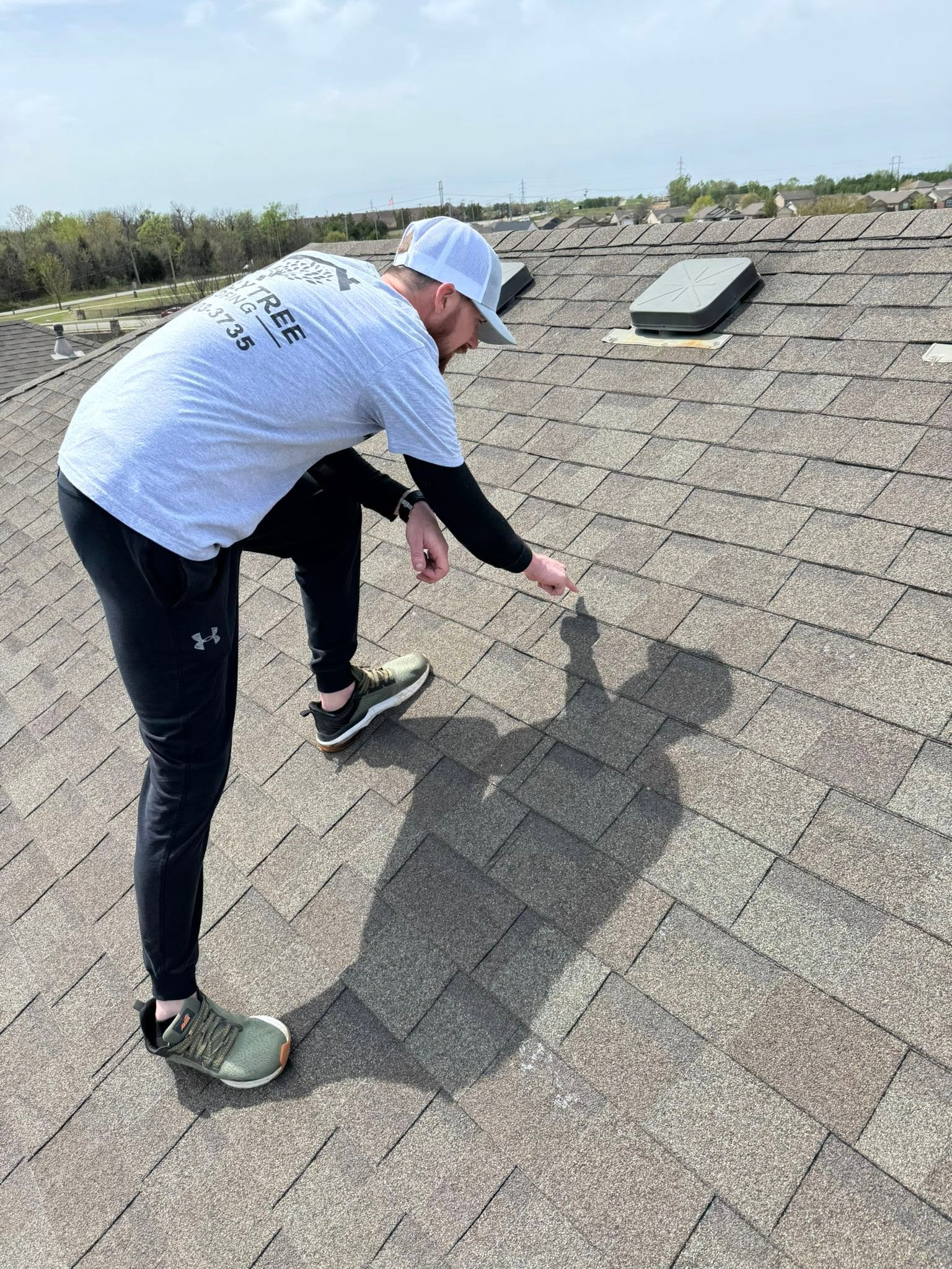 Roofer checking shingles on a residential roof during an inspection