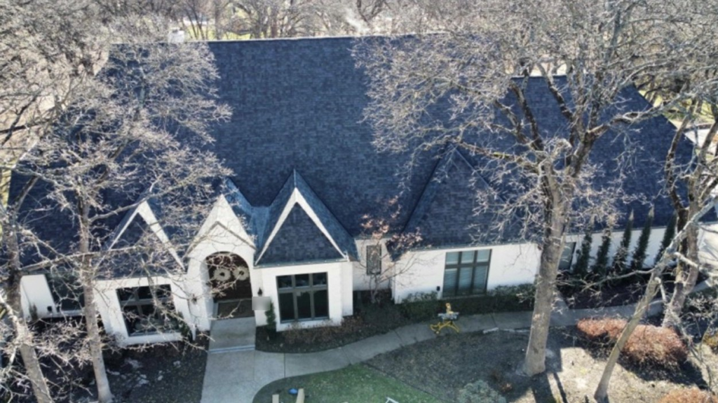 Drone view of a finished roof replacement on a white brick home with steep gables in Tulsa