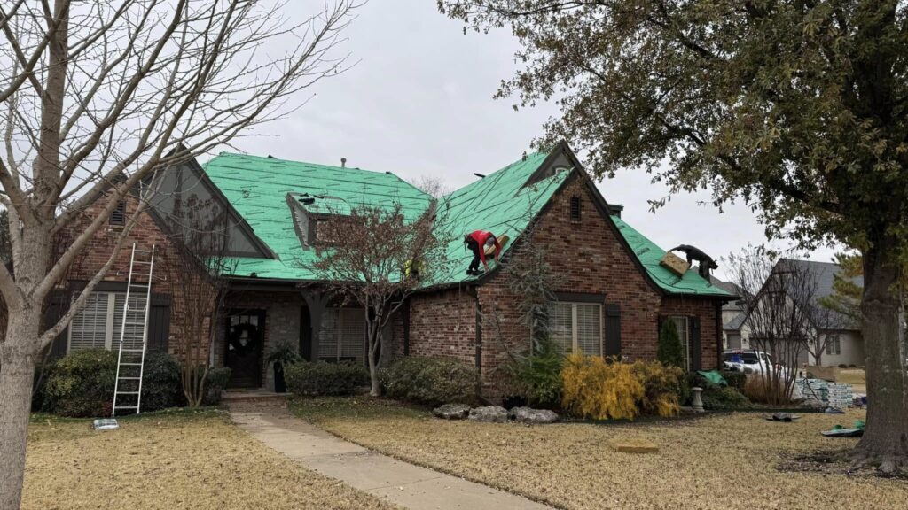 Roofer installing underlayment on a brick home